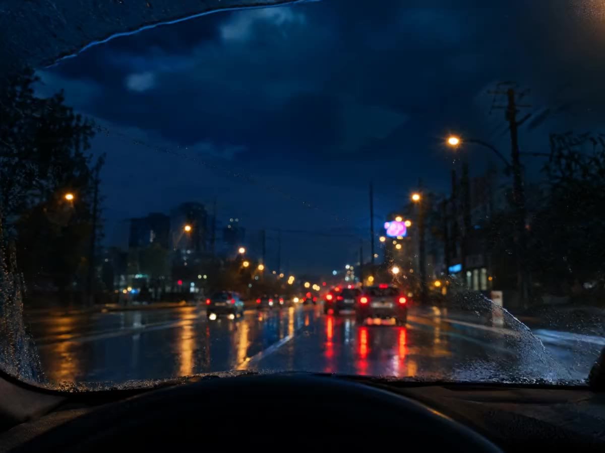 Pare-brise sous la pluie de nuit, balayé par un essuie-glace